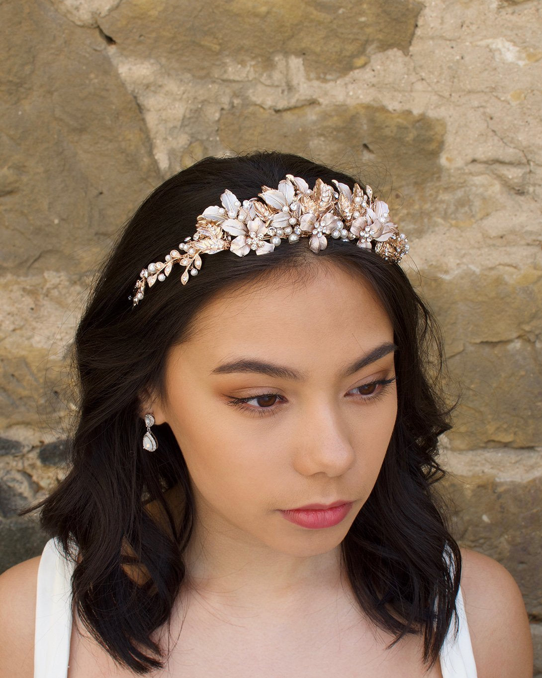 Black haired model wears a pale rose gold and pearl low bridal headband with stone background