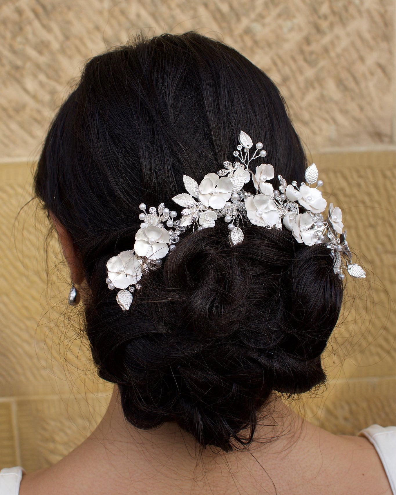 Bride wears Soft Silver Flowers Bridal Comb in her dark hair with a stone wall background