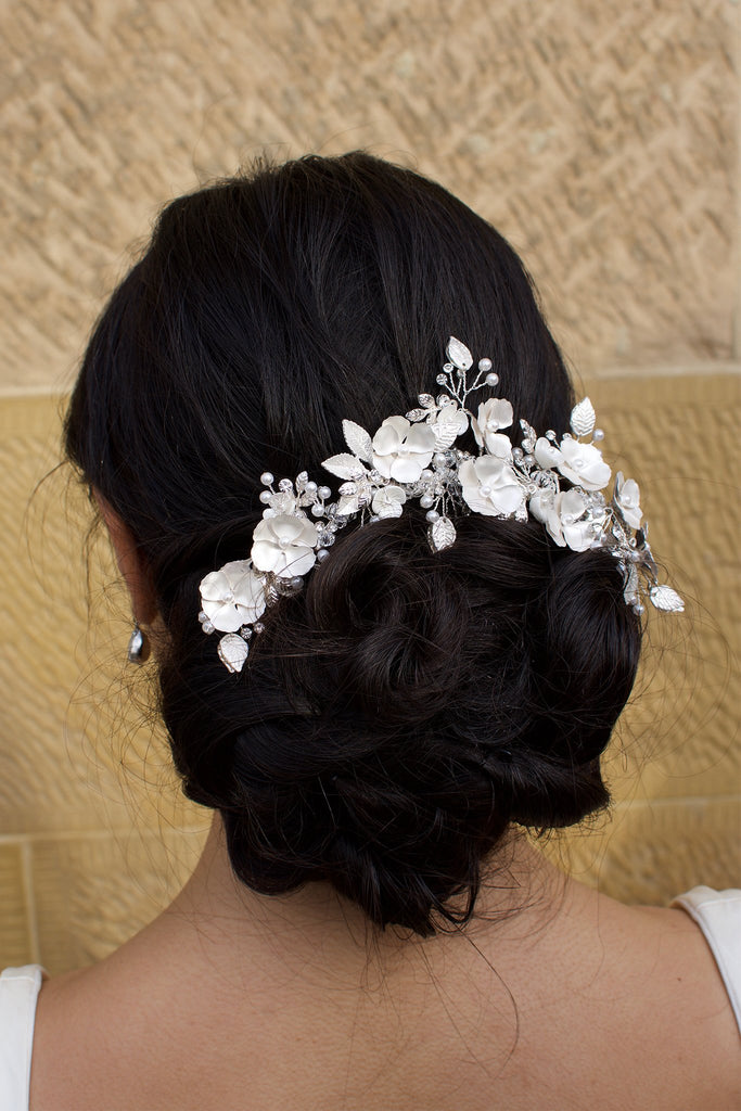 Bride wears Soft Silver Flowers Bridal Comb in her dark hair with a stone wall background
