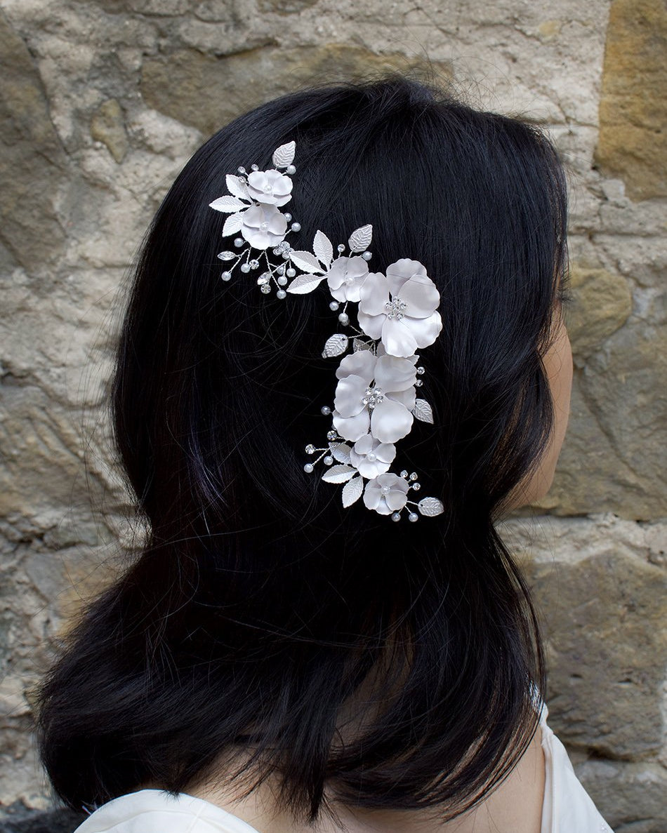 Black haired model wears a white bridal comb in front of a stone wall