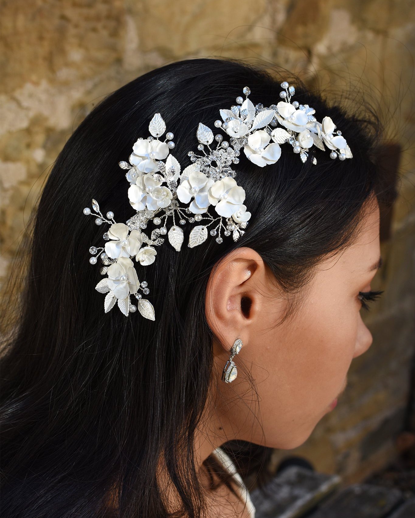 A Dark haired model wears a long side comb with flowers and a small earring