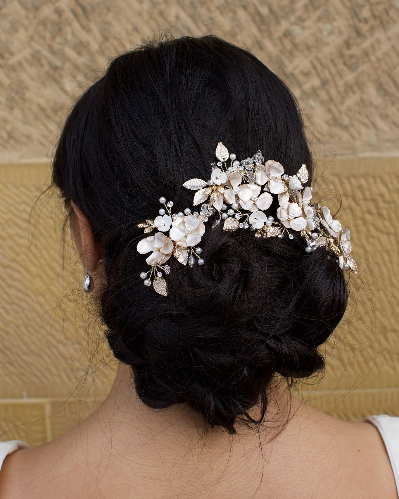 Model Bride wears a Pale Gold Bridal Vine on her dark hair with a wall as background