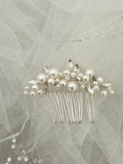 Silver hair comb with pearls on a light gray background