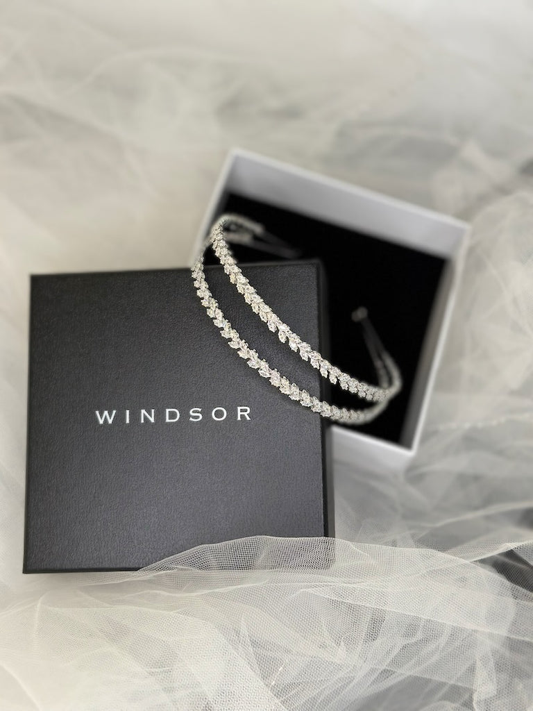 a two row silver crystal headband resting in an open box 