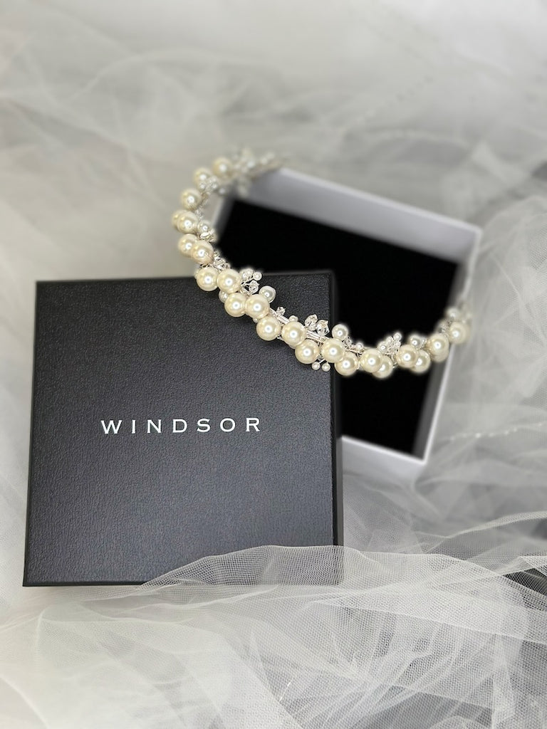 a pearl bridal headband with silver frame on a black display box