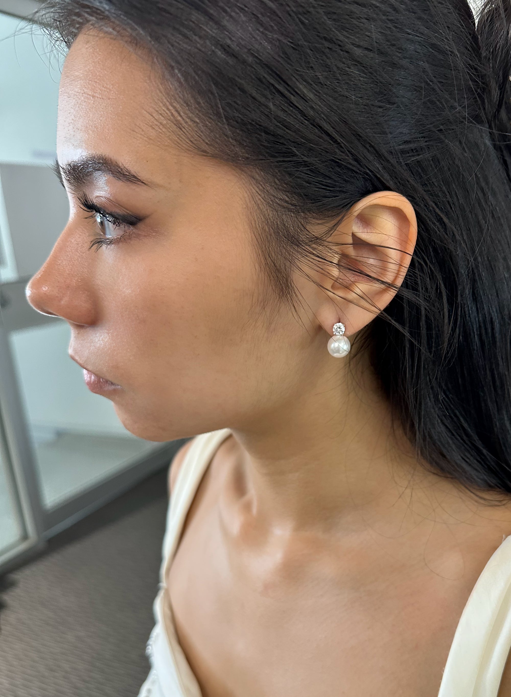 Close-up of a woman wearing pearl earrings in an indoor setting