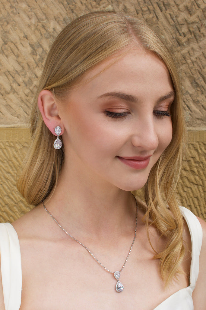 Blonde Bridal Model wearing a short pear shape drop earring with a sandstone backdrop