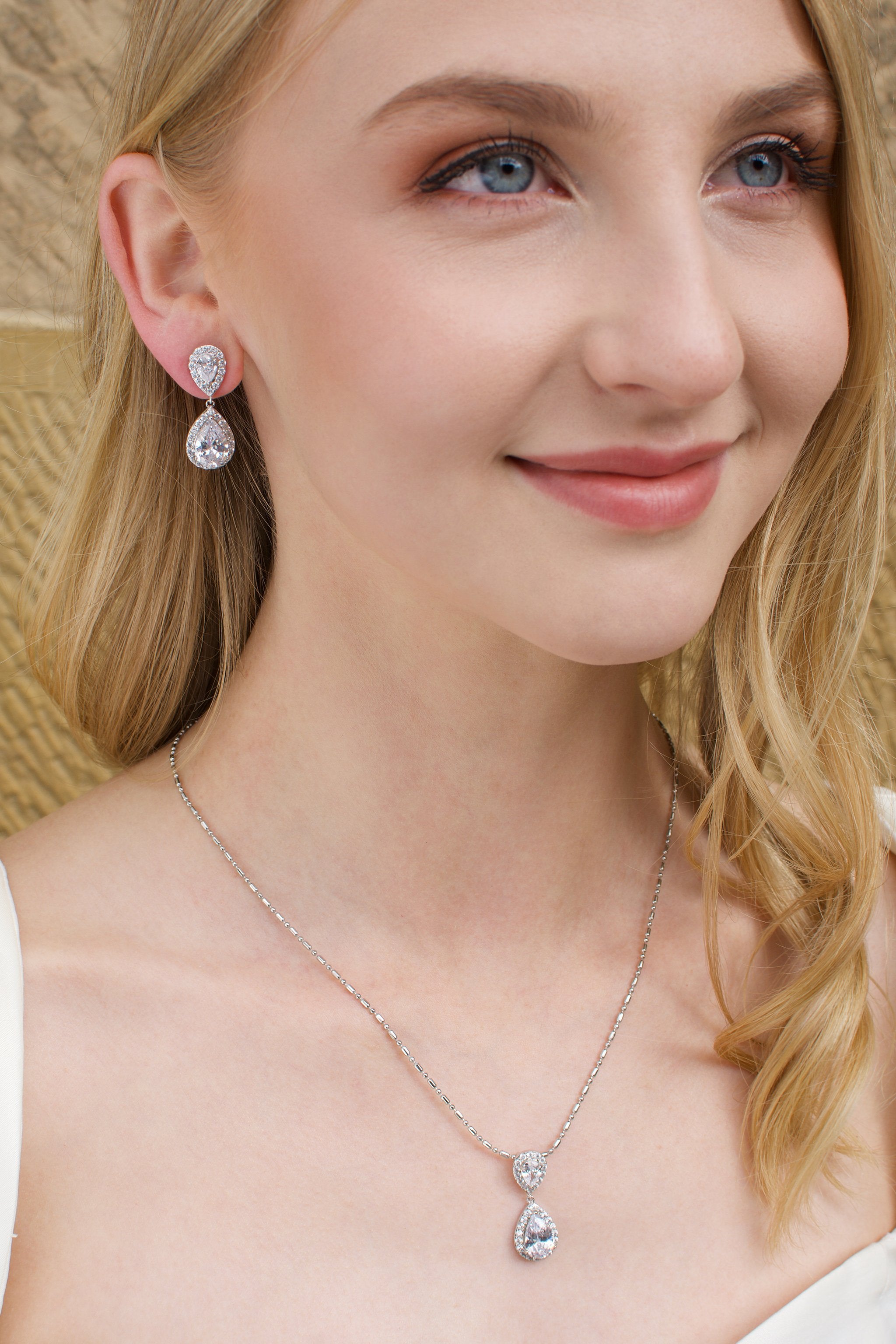 Blonde Model earring a matching pear shape earring and pendant necklace with a sandstone backdrop