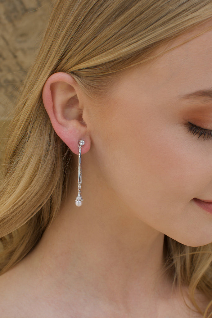 A long silver bridal earring with a hanging pearl worn by a blonde model