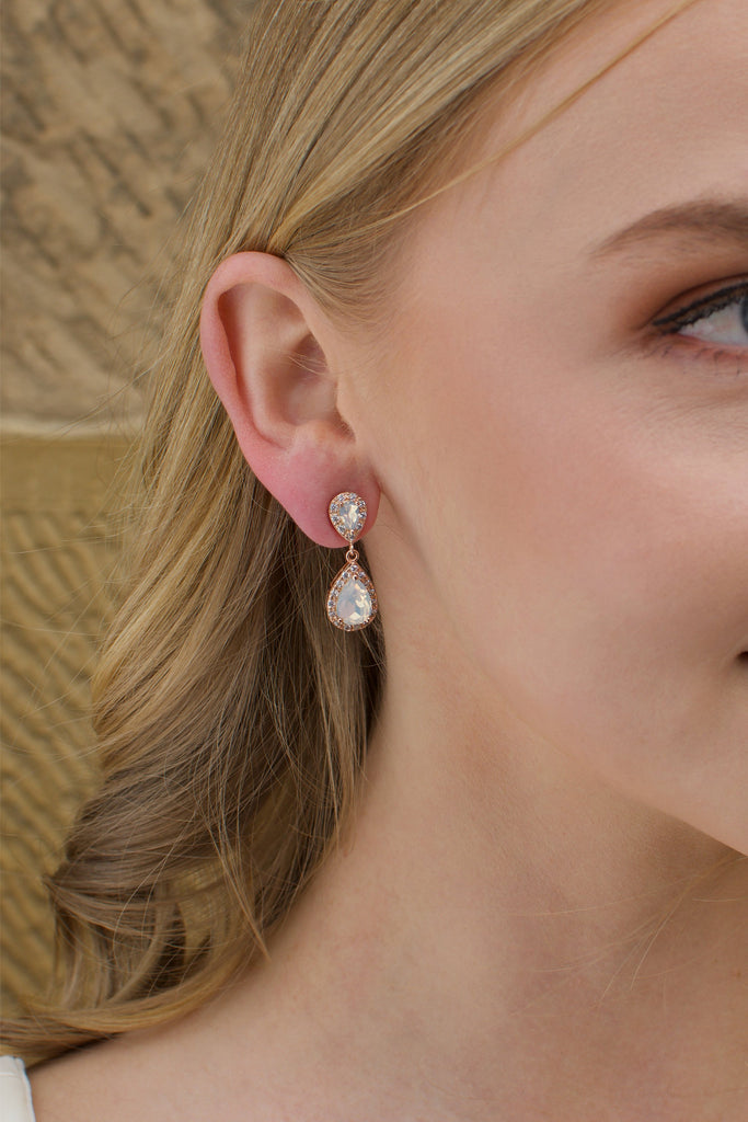 A blonde model bride wears a double teardrop earring with white opal colour stones