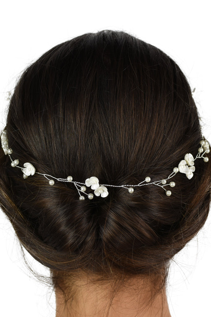 The back of a dark model's head wearing a silver vine with pearls
