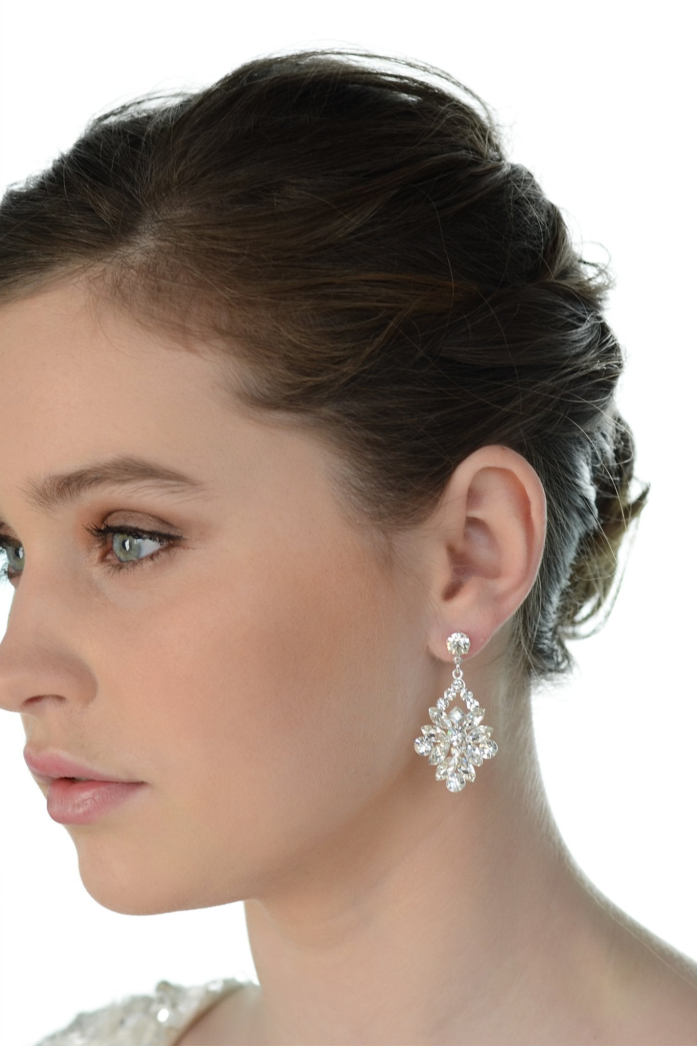 A dark haired model wears a wide drop earring with a white background