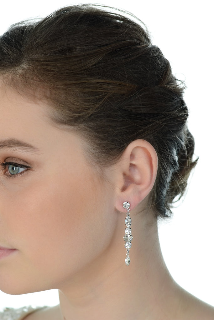 A model wears a long thin bridal earring with a white background