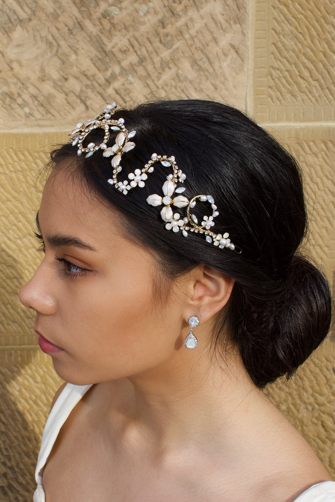 A side view of a model with dark hair wearing a gold bridal headband