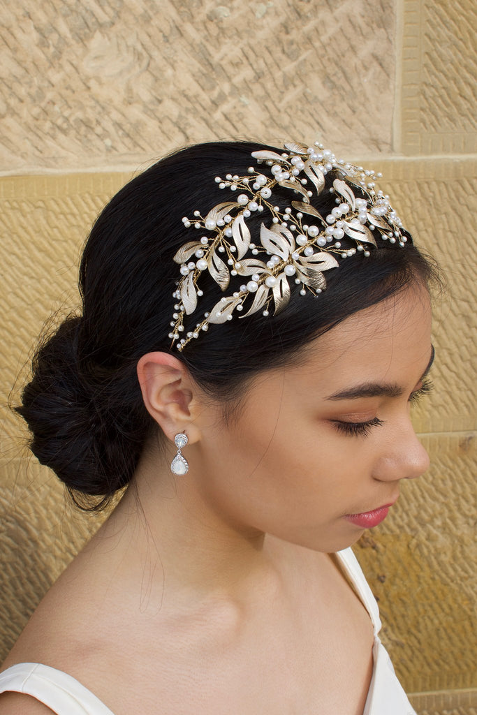 Double row pale gold headband with pearls worn by a dark hair model with a sandstone wall