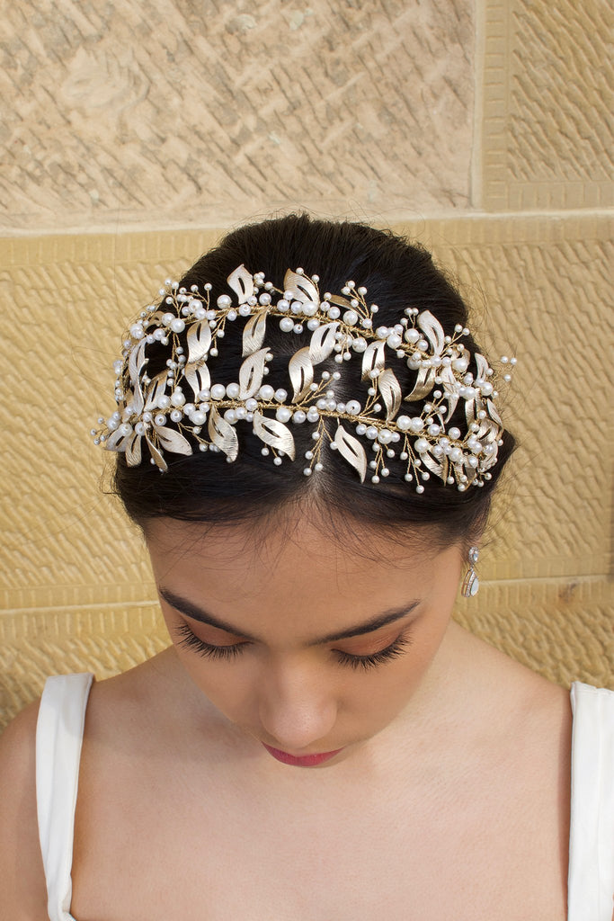 Double row pale gold headband with pearls worn by a dark hair model with a sandstone wall