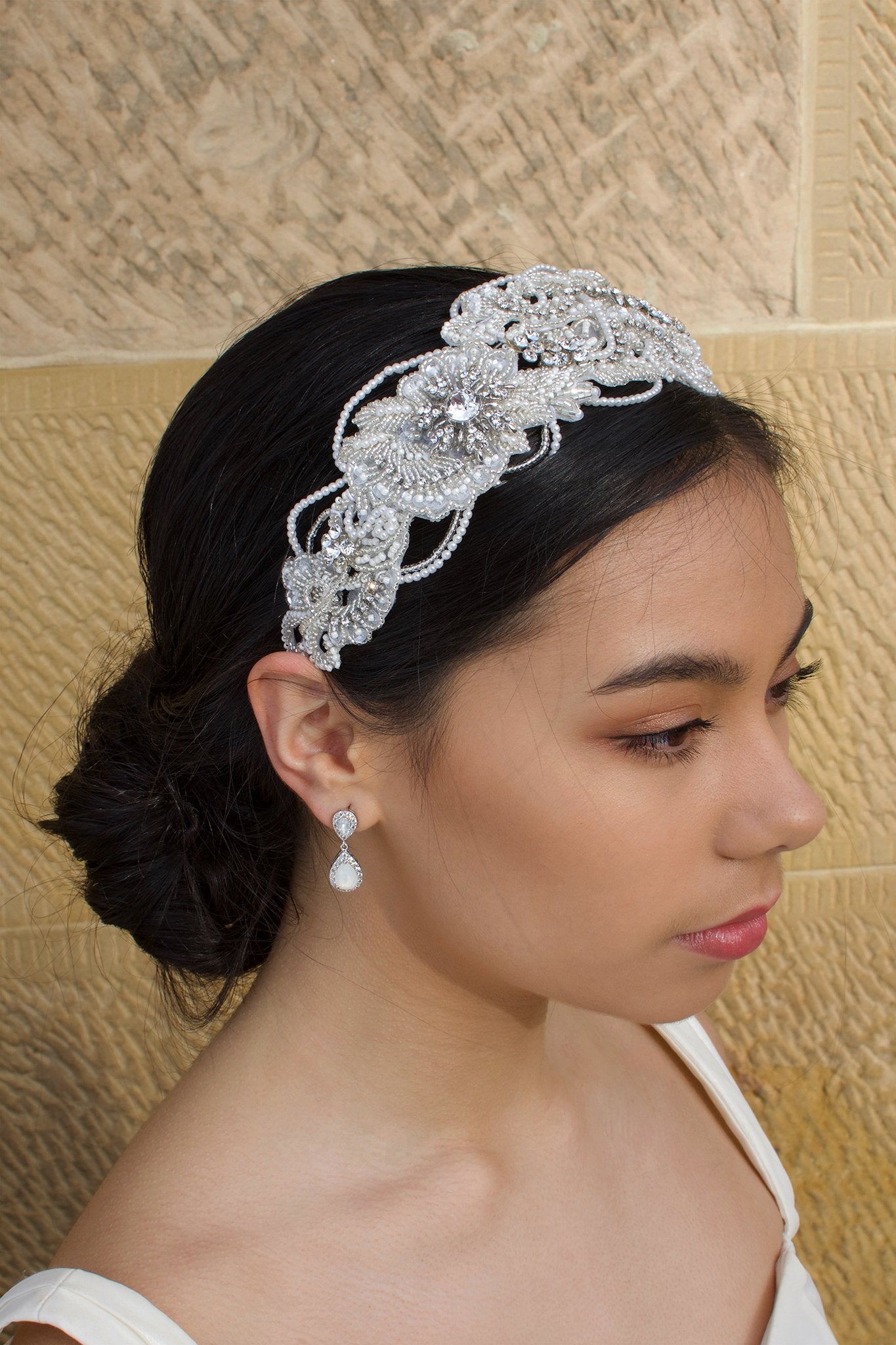 Seed Pearl wide headband worn by a black hair bridal model with a stone background