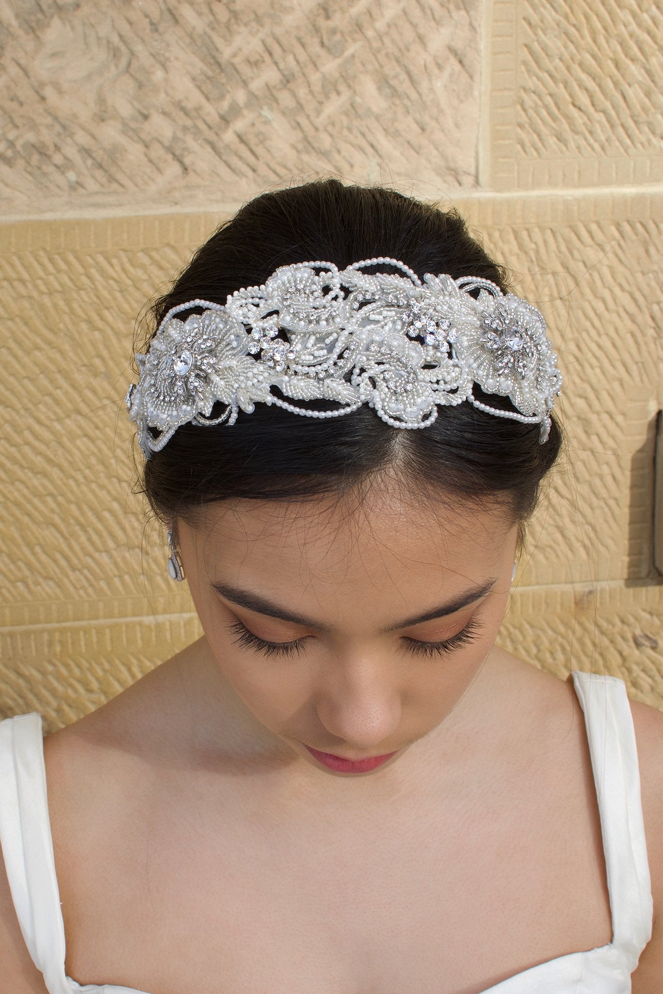 Top View of a dark hair model wearing a seed pearl handmade Bridal Headband with a stone background