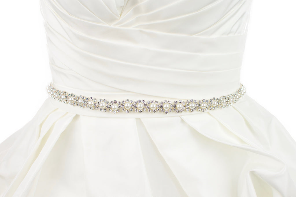A narrow pearl bridal belt with rings of crystals around the pearls is worn on an ivory bridal gown 
