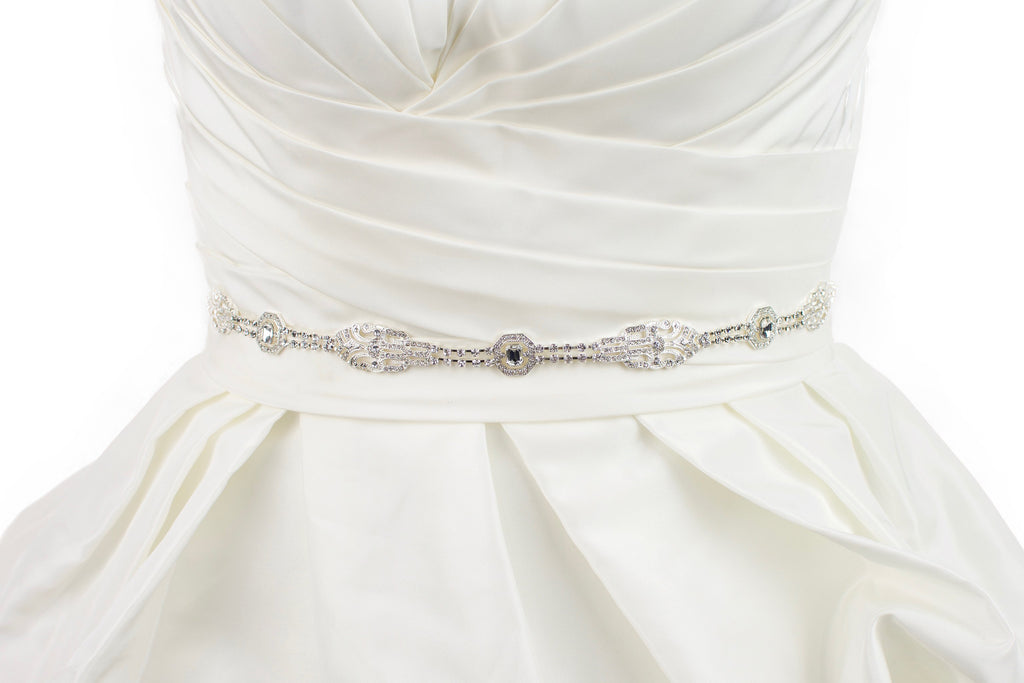 A narrow silver chain bridal belt worn on an ivory wedding gown with a white background