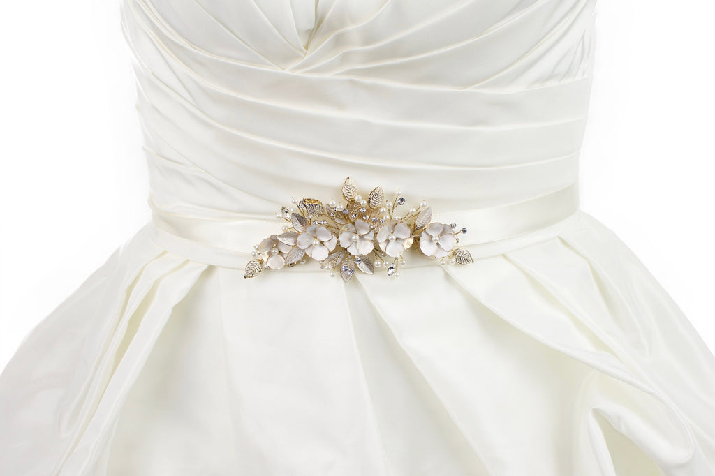 Soft pale gold flowers on an ivory satin bridal belt worn on an ivory bridal gown