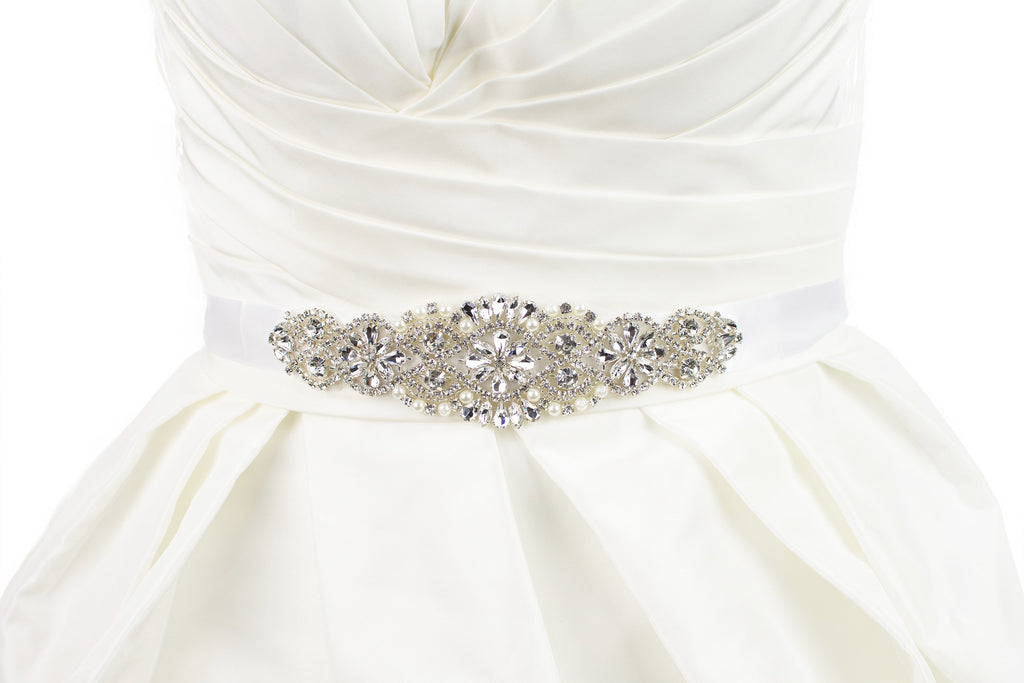 A bridal belt with crystals and pearls that is quite short on a satin ribbon worn on an ivory bridal gown