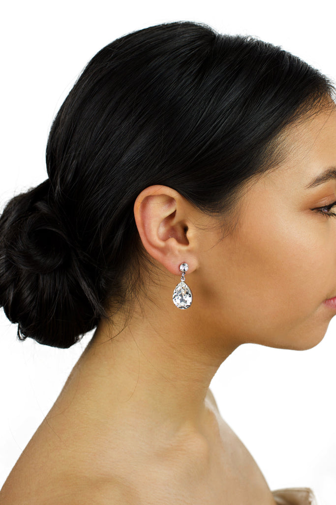 Dark haired model wears a silver earring with a clear Swarovski stone