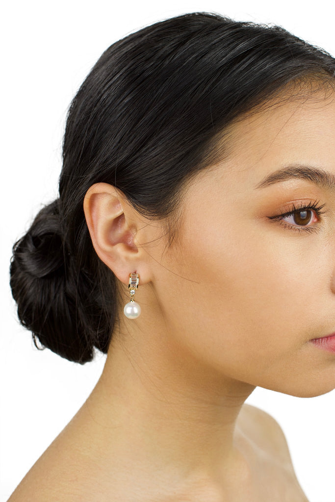 Small Gold and pearl drop earring worn by a dark haired bridal model