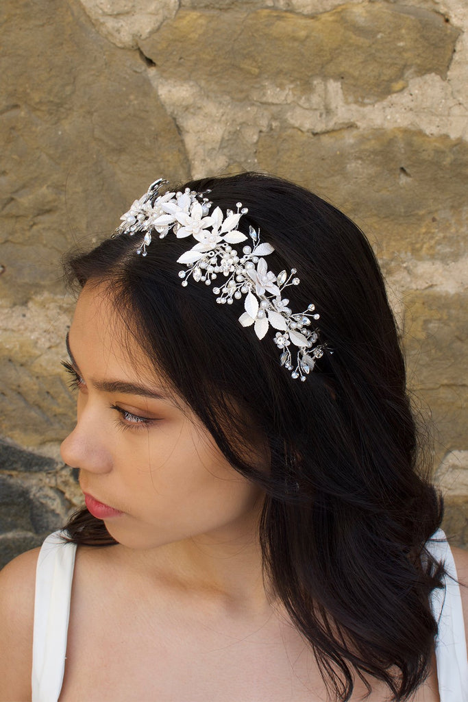 Dark hair bride wears a silver leaves bridal headband with a wall as backdrop