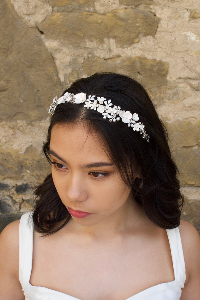 Black haired Bride wearing a White and Silver Flowers headband with a stone wall background