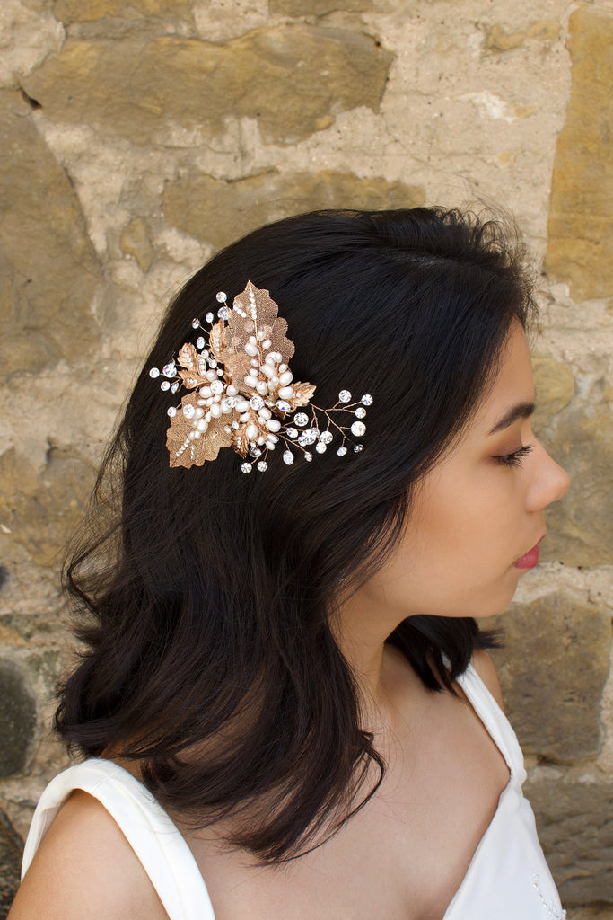 Filigree leaves side comb with freshwater pearls worn by a dark hair model in front of an old stone wall