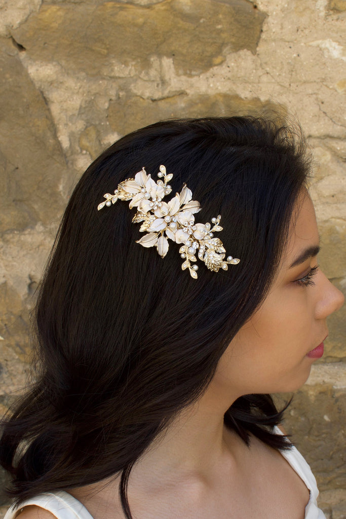 Pale Gold and peal side comb worn by a dark haired bride with a stone wall backdrop