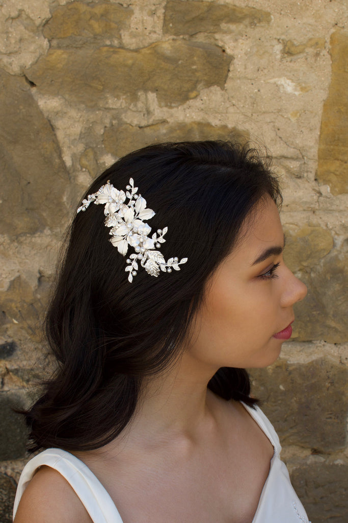 Soft Silver Side Comb with leaves and flowers worn by a dark hair bride with a stone wall backdrop