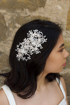 Model wears a large silver side comb on her dark hair with a stone wall background