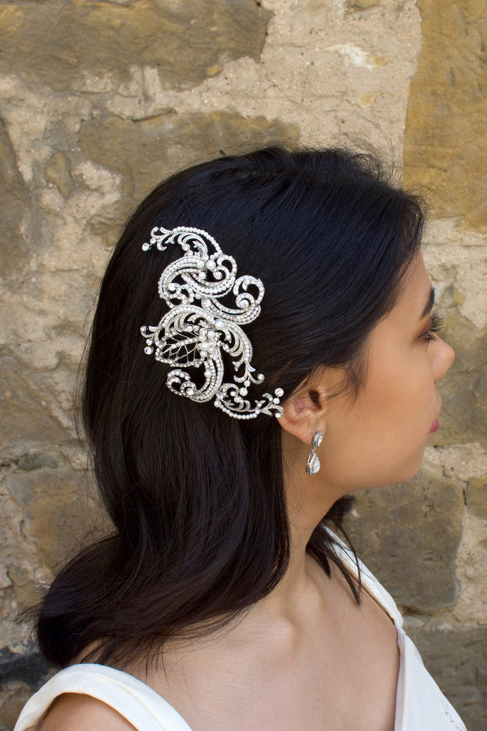Model Bride wears a swirling side comb in her black hair with a stone wall background
