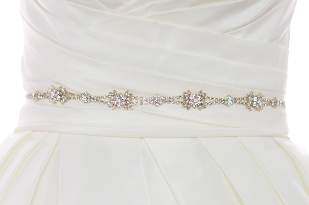 The waist of a bridal dress shown with a narrow Rose Gold belt worn around it with a white background