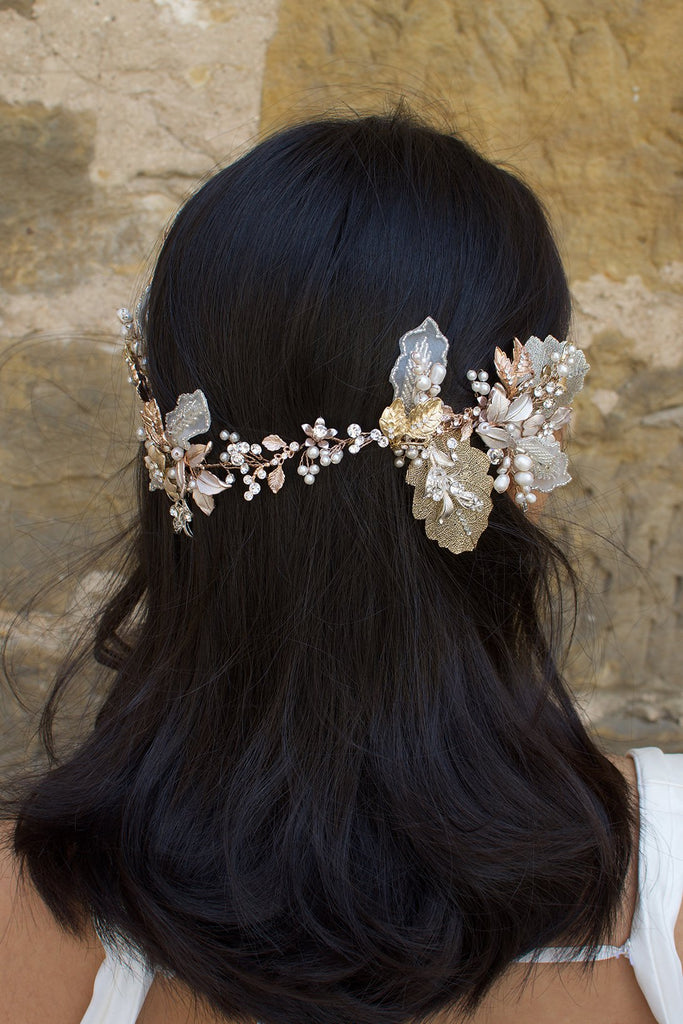 A dark haired model wears a Bridal Vine in Silver, Gold and Rose Gold with a background of a stone wall