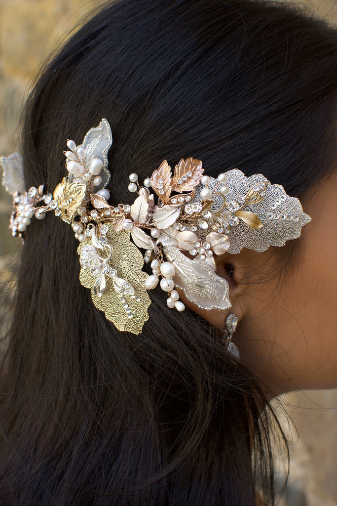 A dark haired model with hair down wears a Bridal Vine in Silver, Gold and Rose Gold with a background of stone