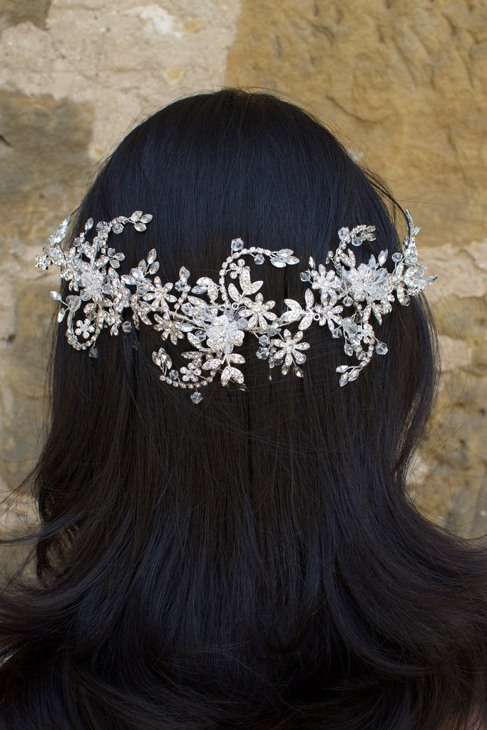 Silver and crystal headband worn at the back of a models head with a stone wall background