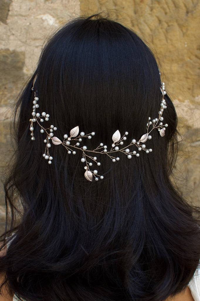 The back of a black haired model wearing a very fine wire bridal vine with leaves and pearls