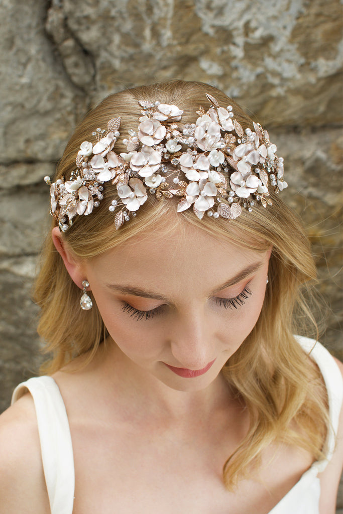 Blonde  Haired model wears a wide headband of flowers with the background of a stone wall