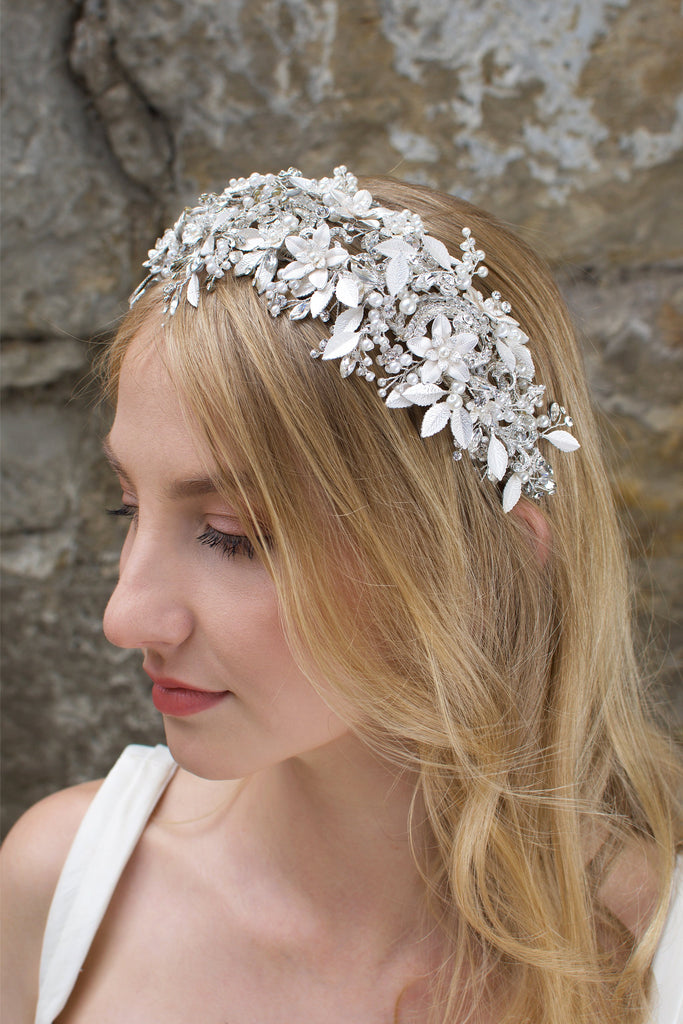 A bride with blonde hair wears a wide silver flowers headband with leaves