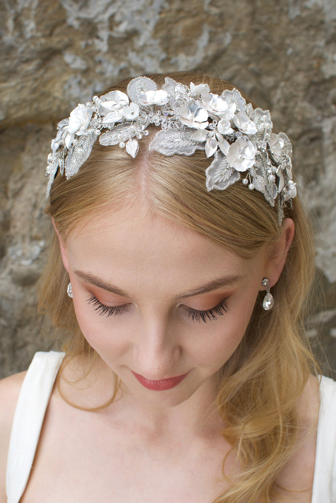 Lace Headband with white flowers worn by a blonde bride with a wall backdrop