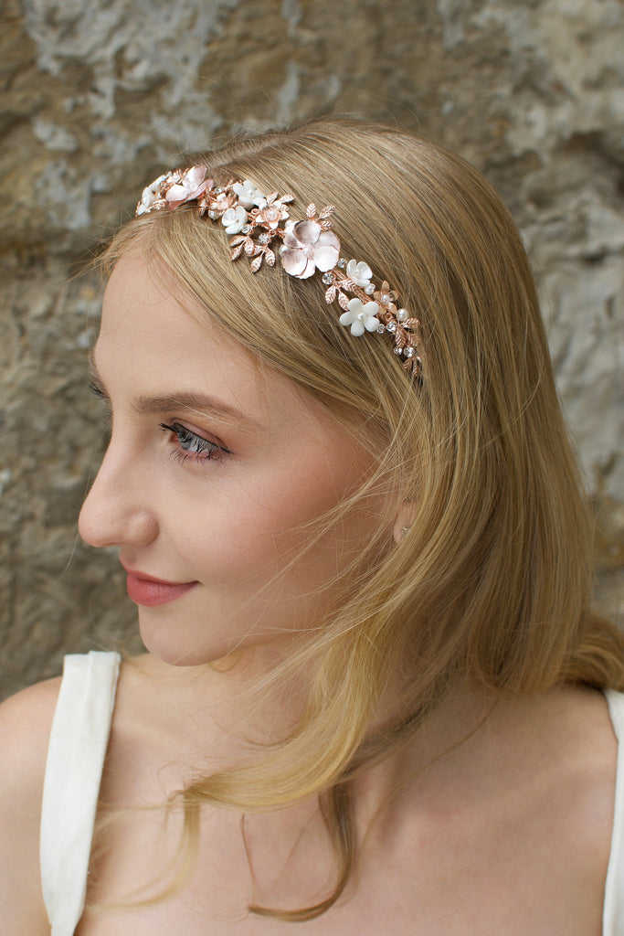 Blonde haired Bridal model wearing a pale rose gold bridal headband with stone background