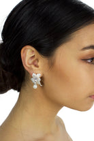 Flower and pearl soft silver earring worn by a dark haired bridal model