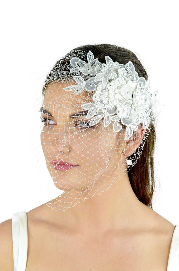 A white lace side comb with a fascinator veil attached worn by a dark haired model