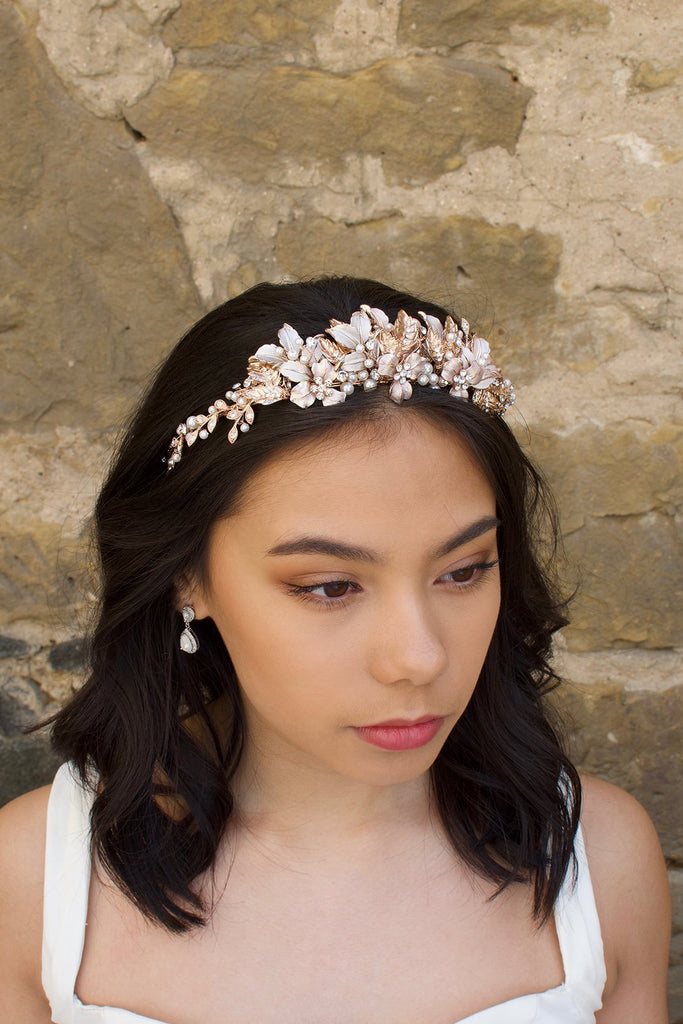 Black haired model wears a pale rose gold and pearl low bridal headband with stone background