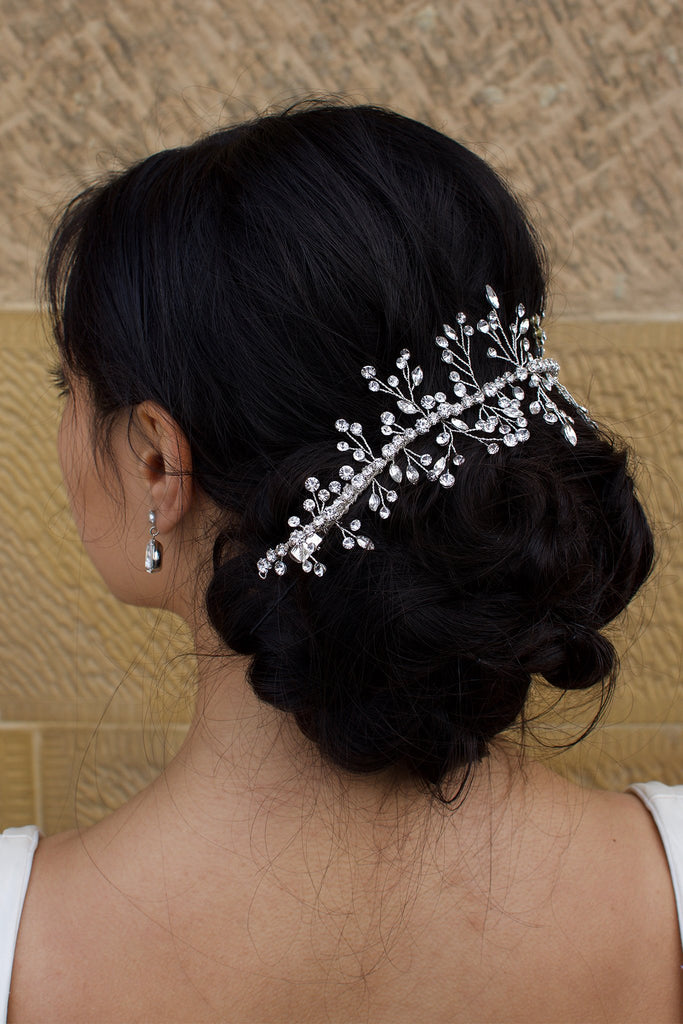 Black Hair Bride wearing a Silver Crystal vine around the back of her hairstyle with a stone wall background
