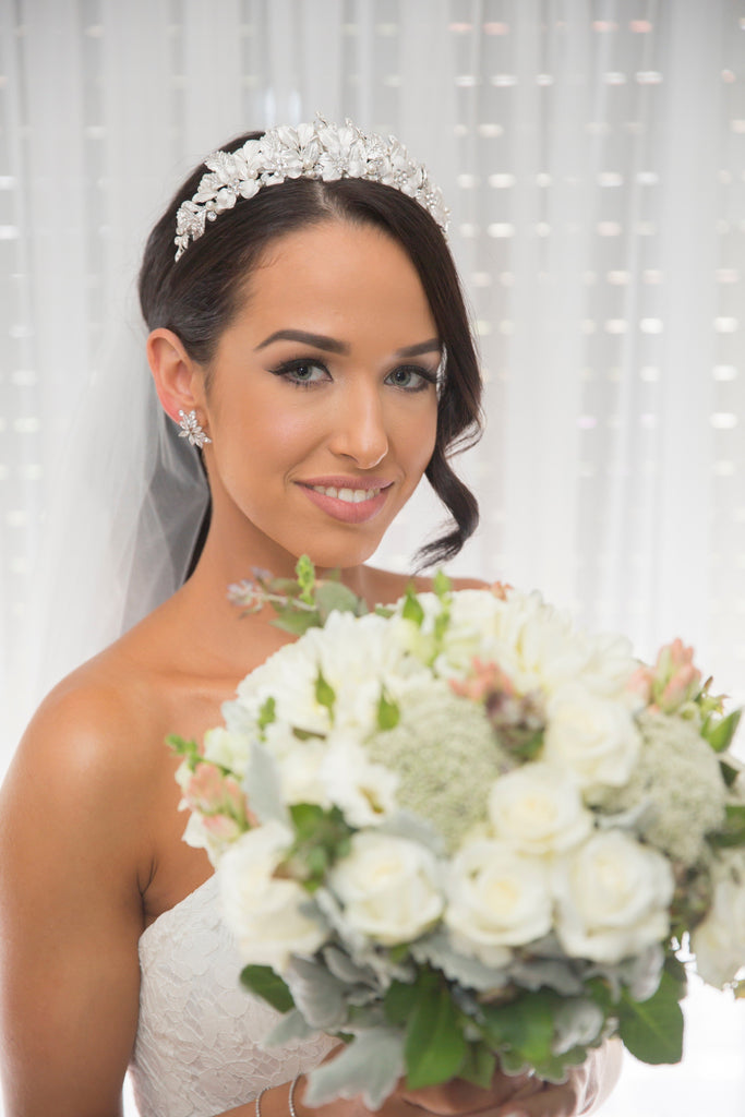Bride with bouquet of flowers wearing a silver leaf crown  and a curl of hair down one side