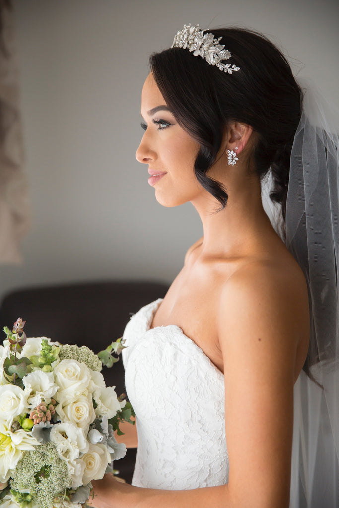 side view of a real bride wearing a silver leaf tiara holding a bouquet of flowers